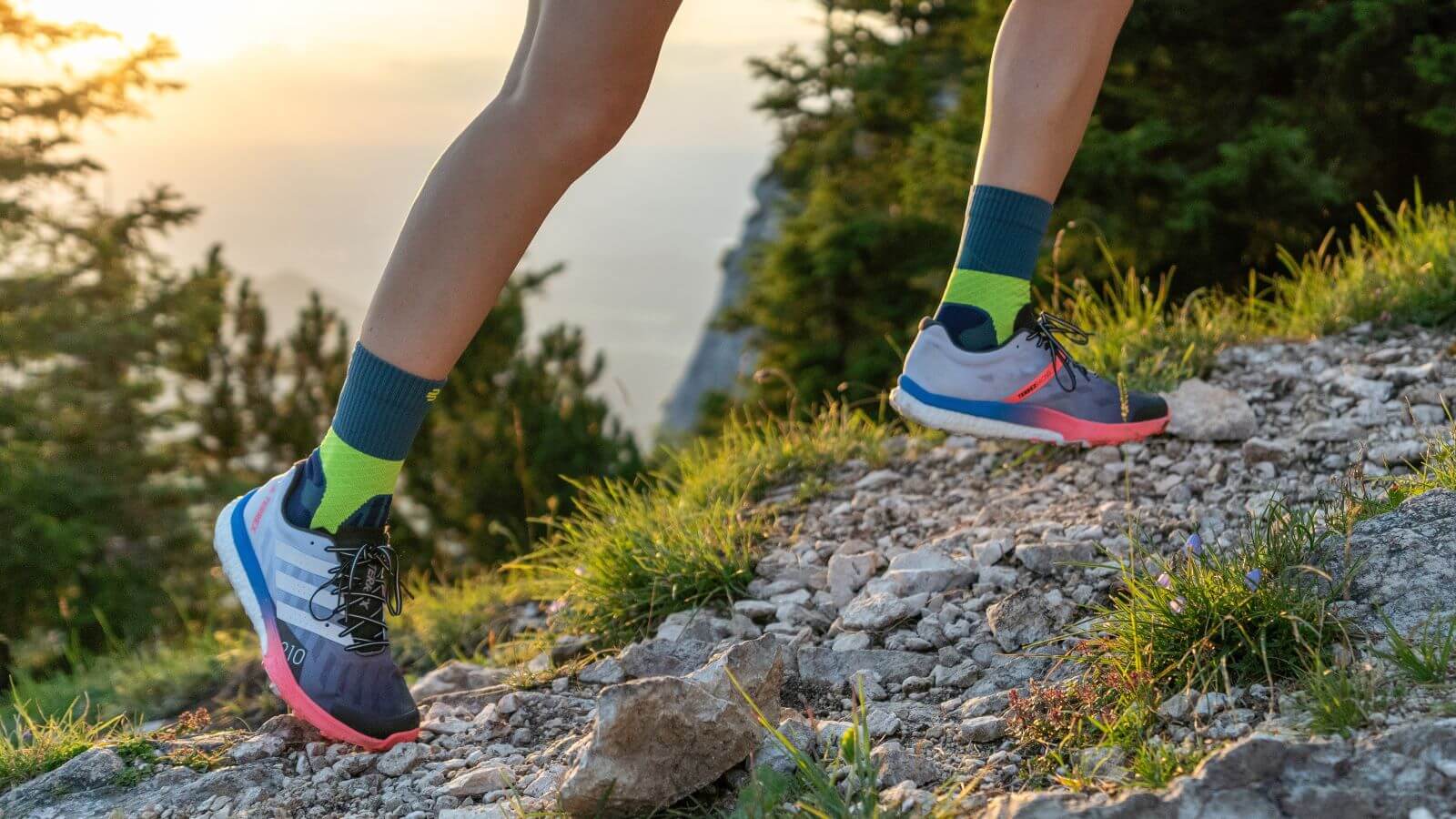Person wearing the Trail Run Mid Cut Socks while running uphill on a gravel trail. Close-up image of a person wearing Bauerfeind's Trail Run Mid Cut Socks while running uphill on a gravel trail through the forest.