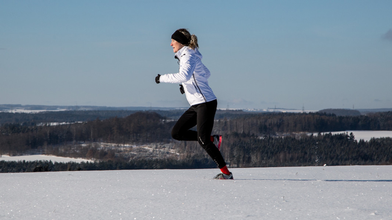 Woman adjusting jacket before running through snowy weather. Woman adjusting the hood of her jacket before running in snowy weather.