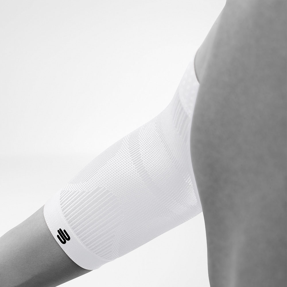 Close-up of a white compression sleeve on a person's elbow, featuring a minimalist black logo