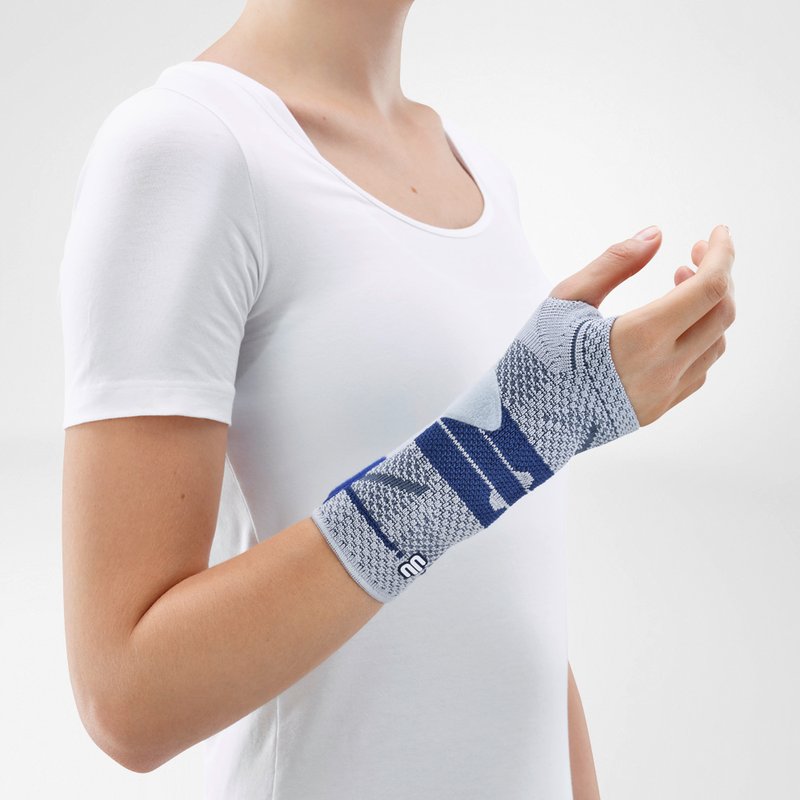 Image of the side of Bauerfeind's ManuTrain wrist brace while being worn by a person in front of a gray background.