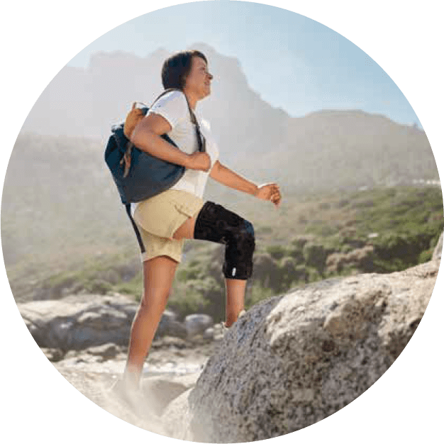 Woman wearing the GenuTrain OA while hiking. Circular icon of a woman wearing Bauerfeind's GenuTrain OA unloader knee brace while hiking on a warm, sunny day.