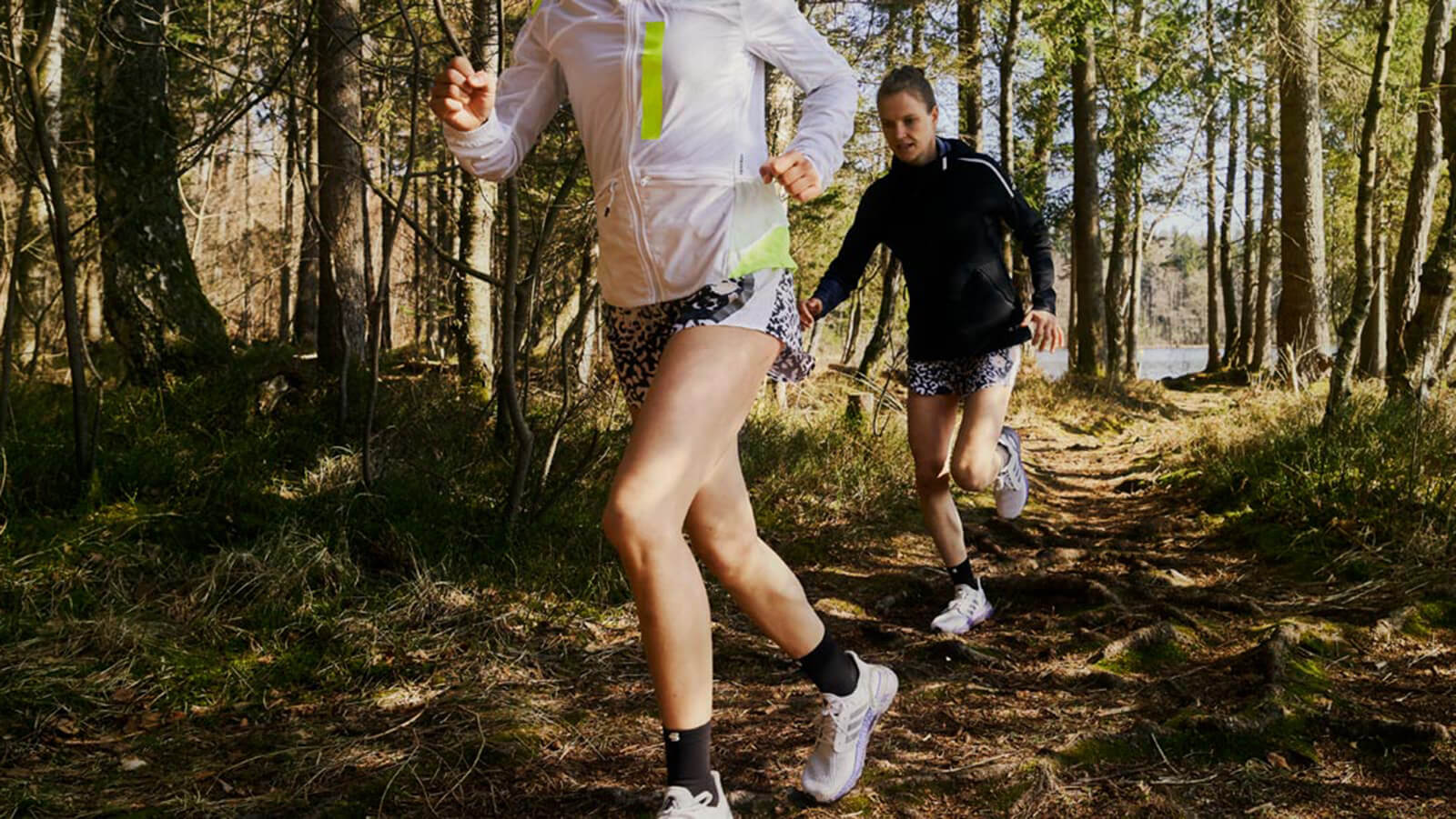 Anna and Lisa Hahner running through a forest trail. Two women running through a forest trail in the morning.