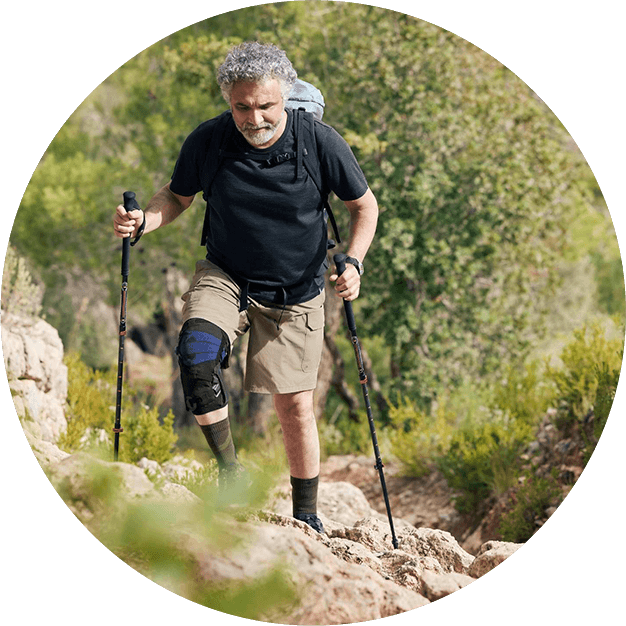Man wearing the GenuTrain OA before hitting a volleyball. Circular icon of a man wearing Bauerfeind's GenuTrain OA unloader knee brace while preparing to hit a volleyball at the beach.