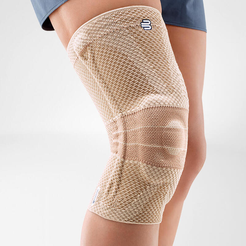 Close-up image of a person wearing Bauerfeind's beige GenuTrain A3 arthritis knee brace.