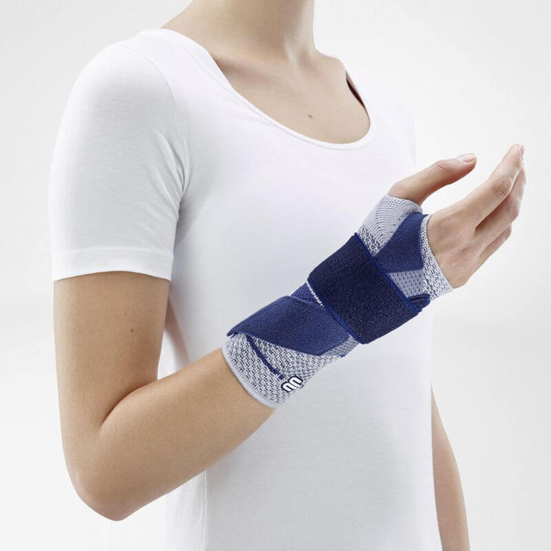 ManuTrain (Titan) With Two-Part Strap System Woman wearing Bauerfeind's ManuTrain wrist brace (titan) while standing in front of a gray background.