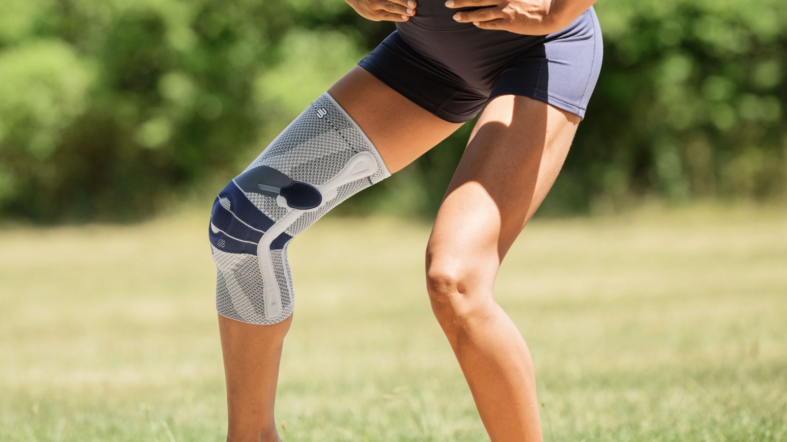 Woman practicing yoga in a fitness center while wearing Bauerfeind's GenuTrain P3 patella knee brace.