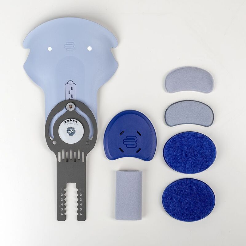 Assorted blue physiotherapy equipment pieces arranged on a white background, including a traction device, foam pads, and gel cushions.
