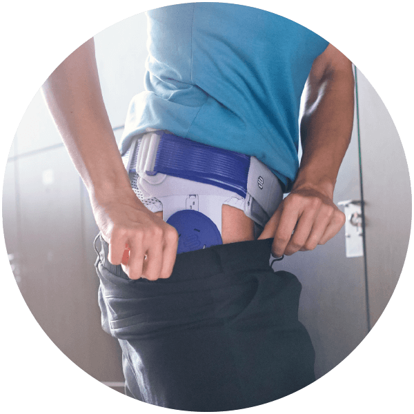 Low-Profile Person donning pants over Bauerfeind's CoxaTrain hip brace in a fitness locker room.