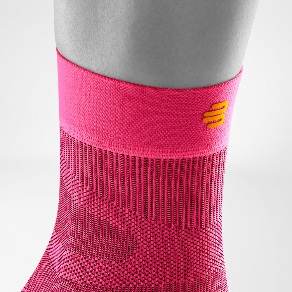 Close-up of a pink compression sock with yellow logo design on a person's leg