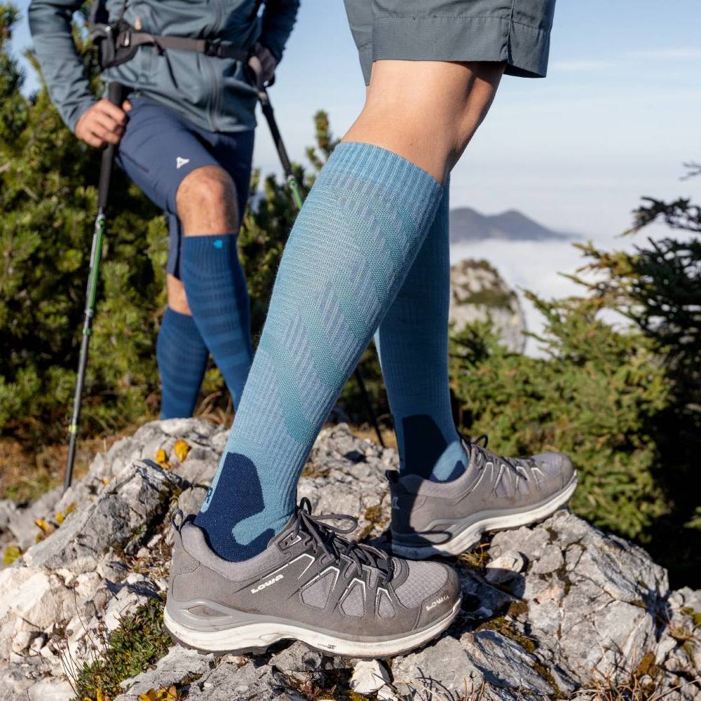 Hiking with Blue Compression Socks on Rocky Mountain Trail Two hikers on a rocky mountain trail wearing blue compression socks and hiking shoes.