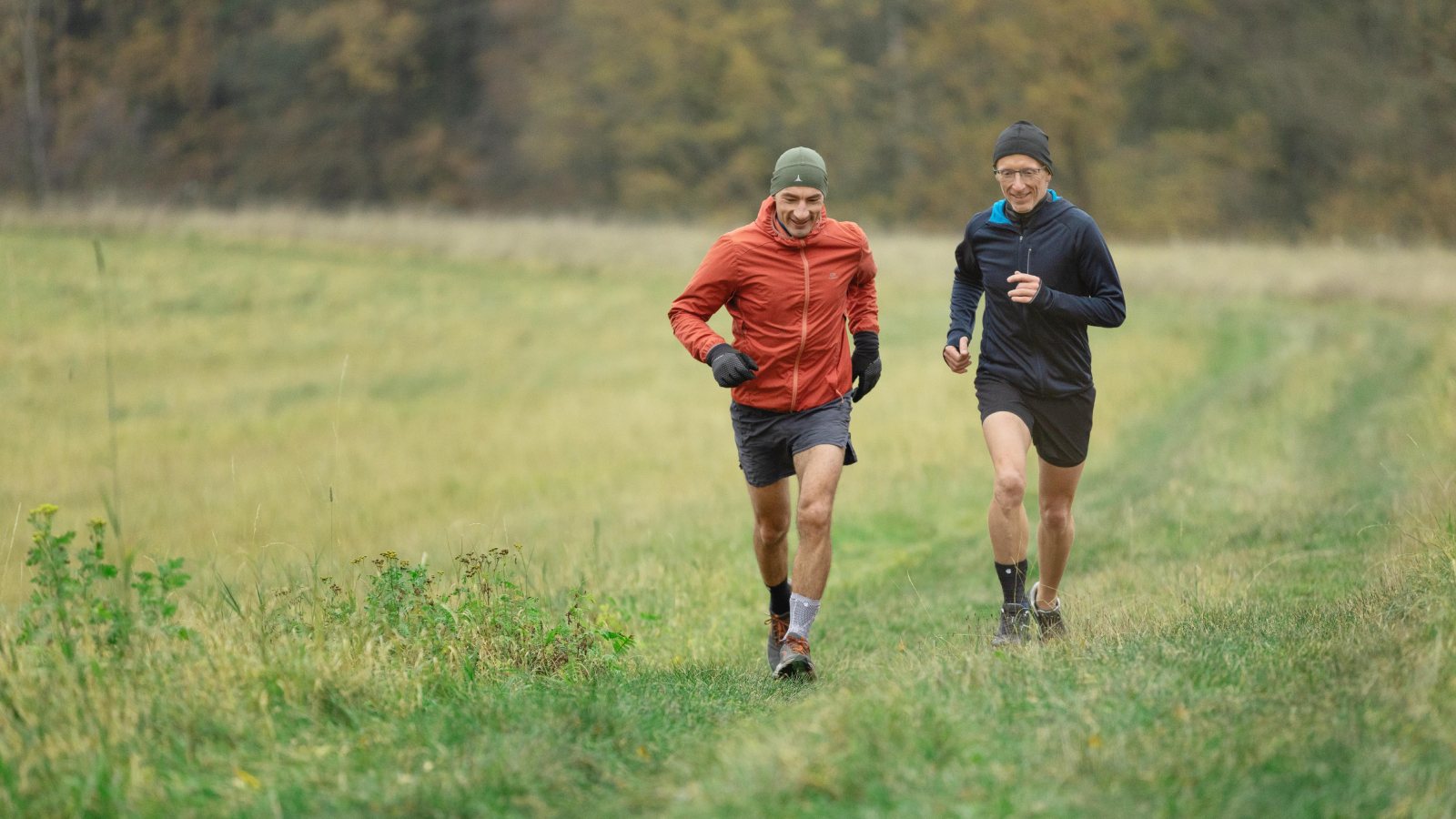 Two men wearing Bauerfeind's AchilloTrain Achilles tendonitis ankle brace while running.