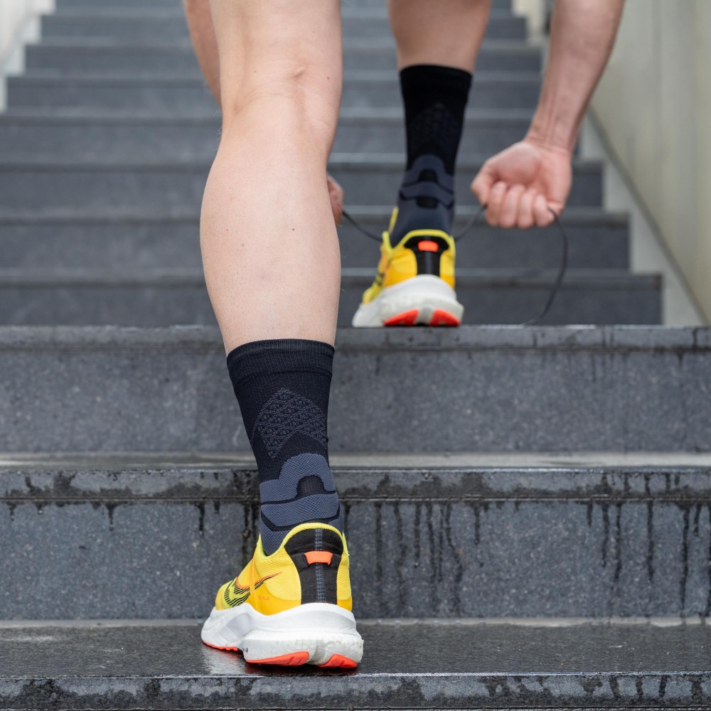 Athlete lacing shoes while wearing the black Run Performance Mid-Cut Socks.