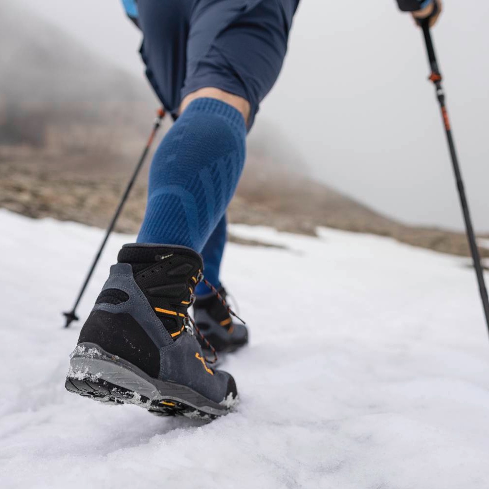 Hiking on a Snowy Mountain with Trekking Poles Close-up of a hiker's boots and trekking poles while walking on a snowy mountain trail.