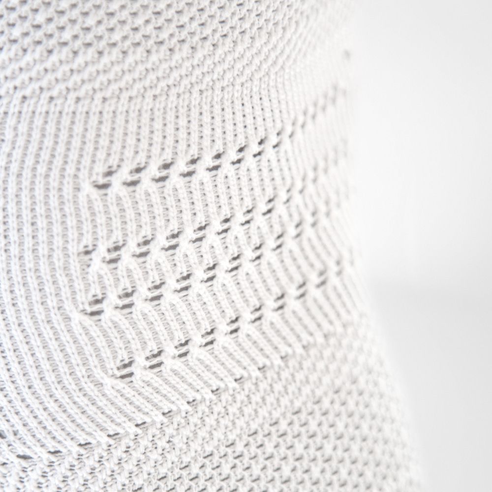 Close-up of white knitted fabric with intricate patterns and texture.