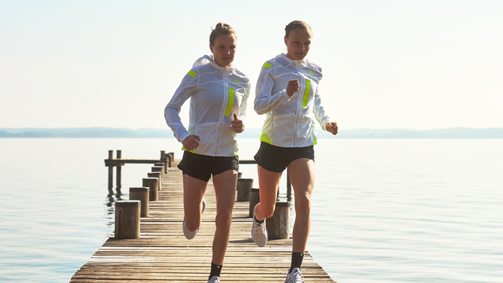 Anna and Lisa Hahner on a morning run near a lake. Two women on a morning run together around a lake.