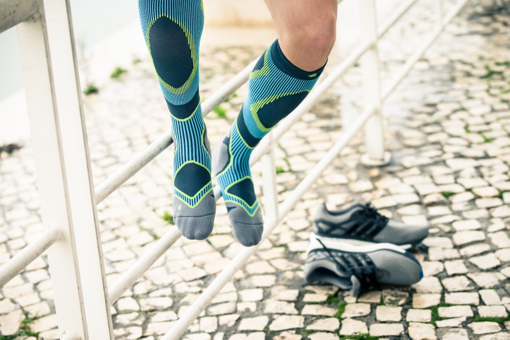Woman wearing the Run Performance Compression Socks while running through a city street. Woman wearing Bauerfeind's Run Performance Compression Socks while running through a city street.