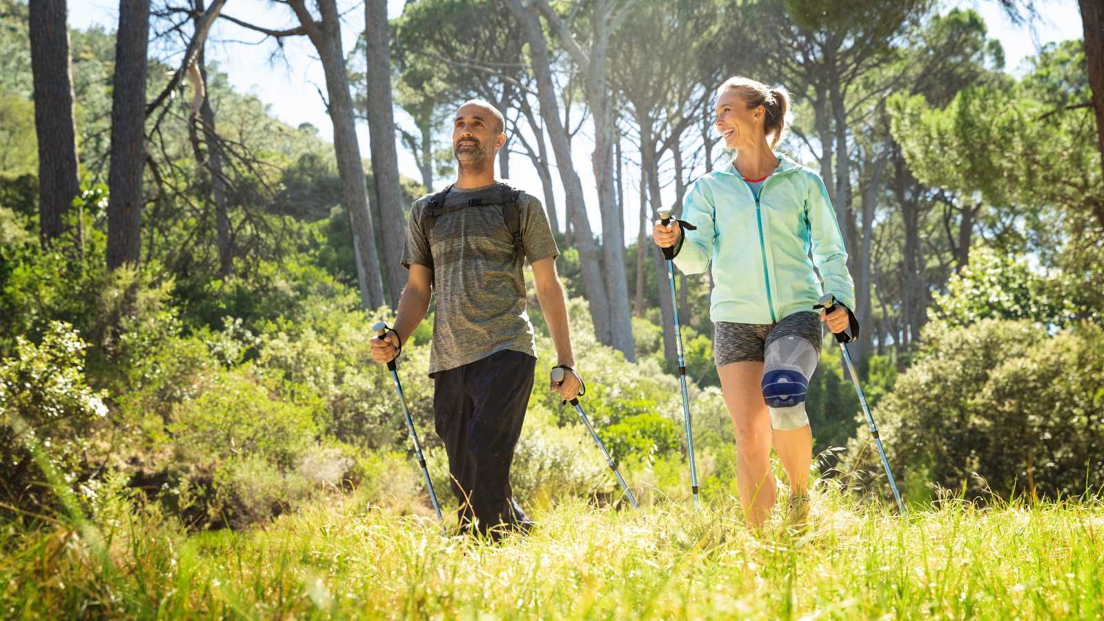 Couple hiking through a grassy trail with the woman wearing the GenuTrain A3. Couple hiking through a grassy trail with the woman wearing Bauerfeind's GenuTrain A3 arthritis knee brace.