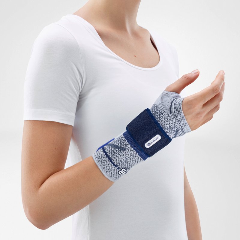 Image of the side of Bauerfeind's ManuTrain wrist brace while being worn by a person in front of a gray background.