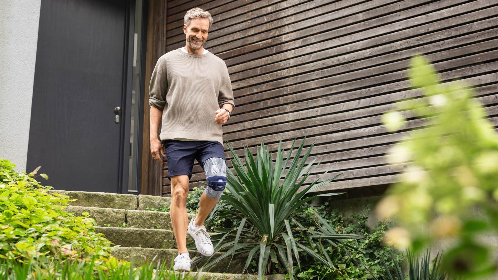 Man walking down steps wearing the GenuTrain A3. Man leaving his house by walking down steps wearing Bauerfeind's GenuTrain A3 arthritis knee brace.