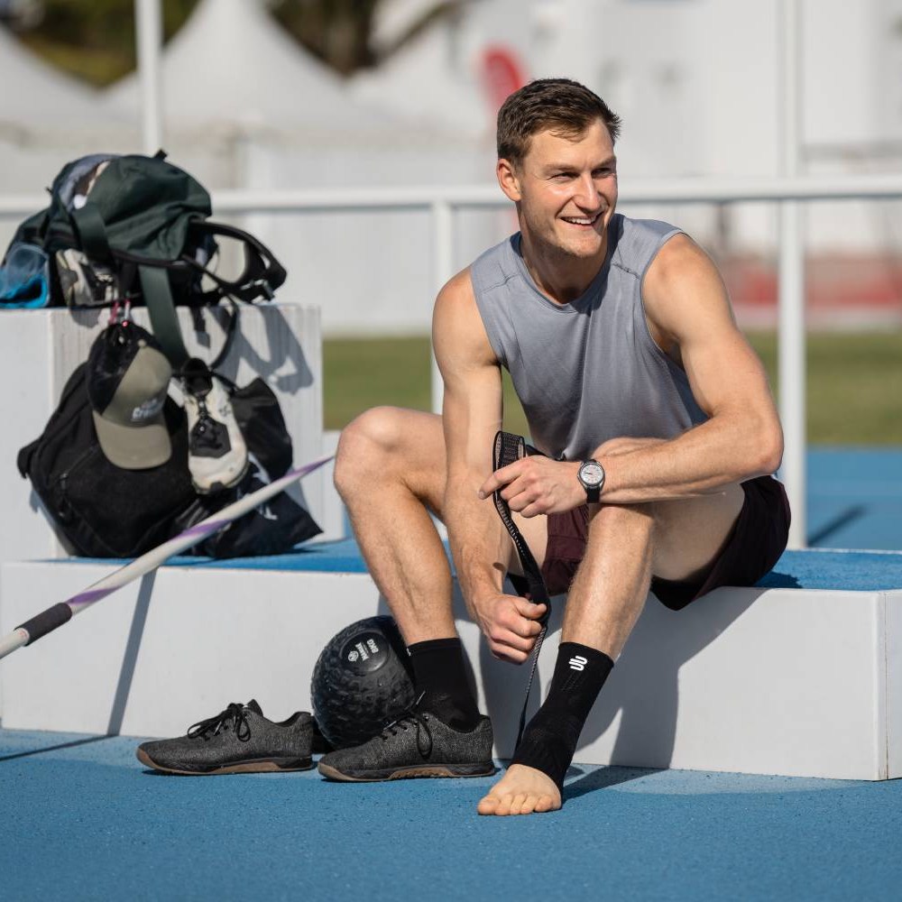 Javelin professional prepares for a outdoor training and puts on a ankle support