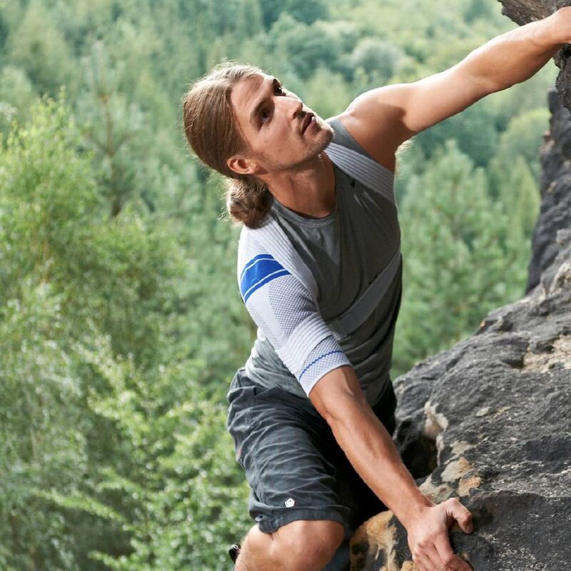 Man climbing the side of a mountain while wearing Bauerfeind's OmoTrain shoulder brace.