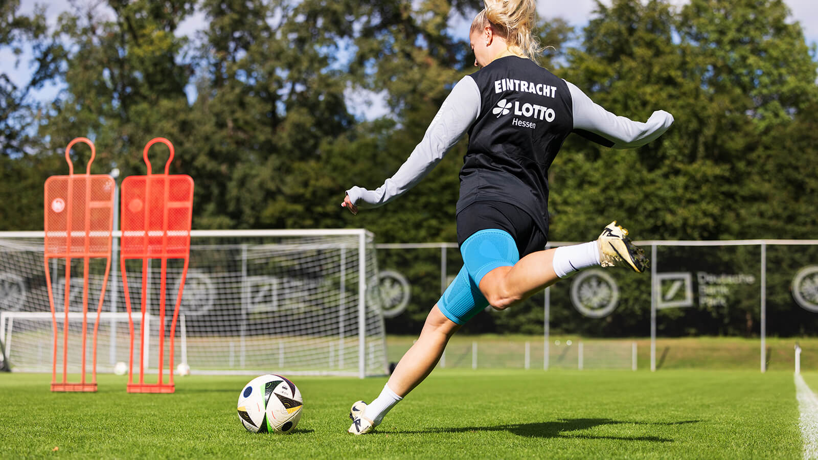 Soccer player wearing the Sports Compression Upper Leg Sleeves while kicking the ball toward the net. Soccer player wearing Bauerfeind's Sports Compression Upper Leg Sleeves while kicking the ball toward the net.