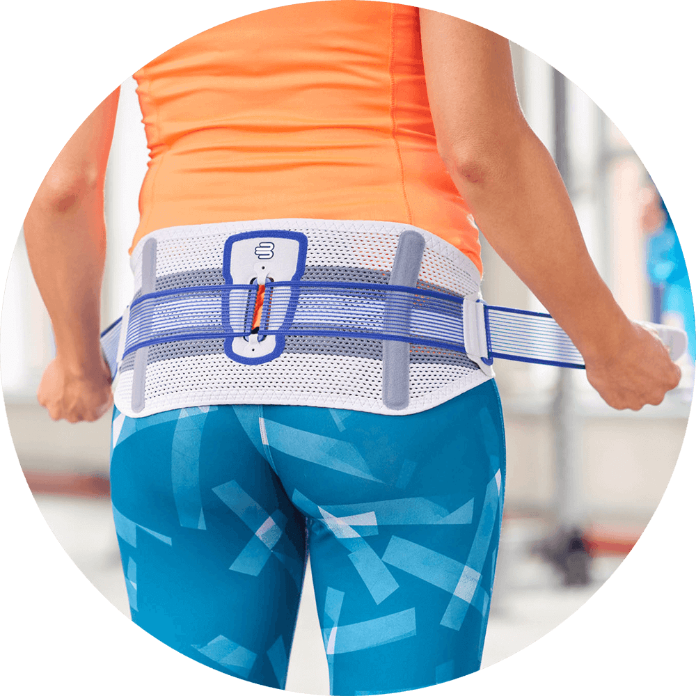 Woman adjusting the tension straps on Bauerfeind's SacroLoc SI joint belt before exercising.