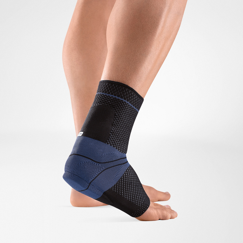 Close-up view of a person wearing a stylish blue ankle support brace on their left foot, ideal for sports and injury prevention.