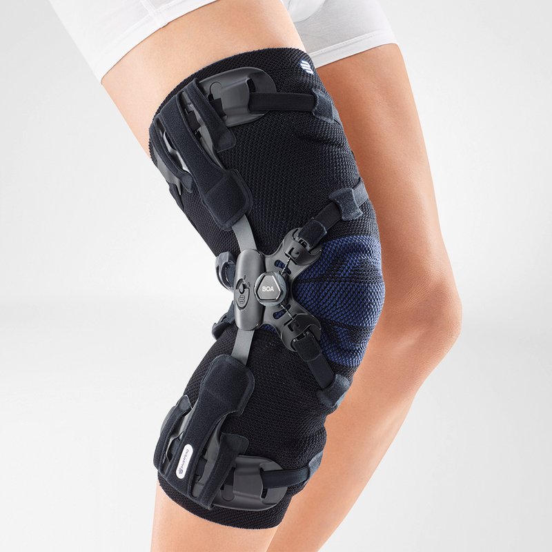 Woman wearing advanced knee brace for joint support and injury recovery, featuring adjustment dials and straps on a white background