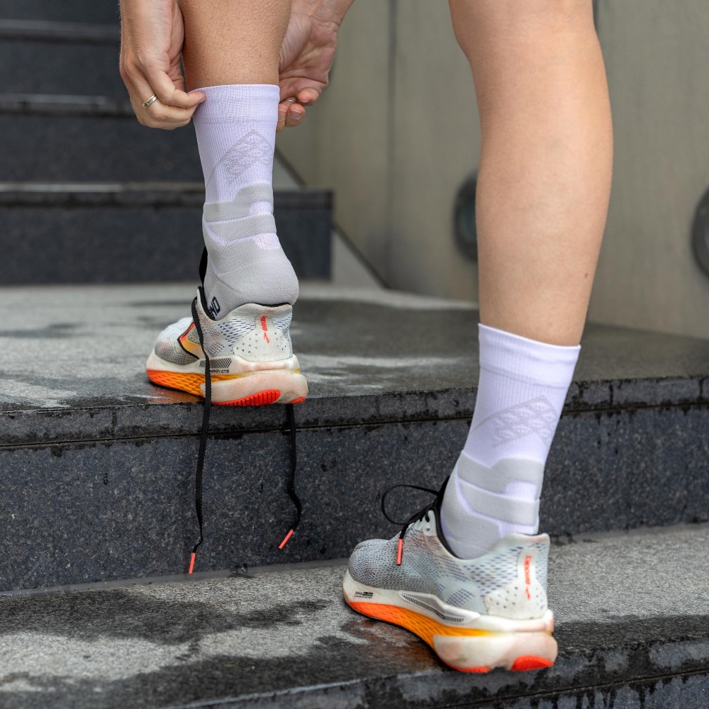 Athlete lacing shoes while wearing the white Run Performance Mid-Cut Socks.