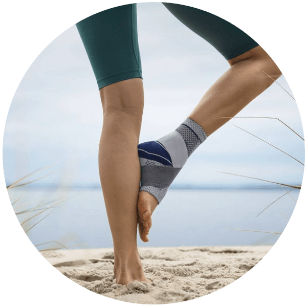 Woman practicing yoga on the beach while wearing the MalleoTrain Plus. Woman practicing yoga on the beach while wearing Bauerfeind's MalleoTrain Plus ankle brace.