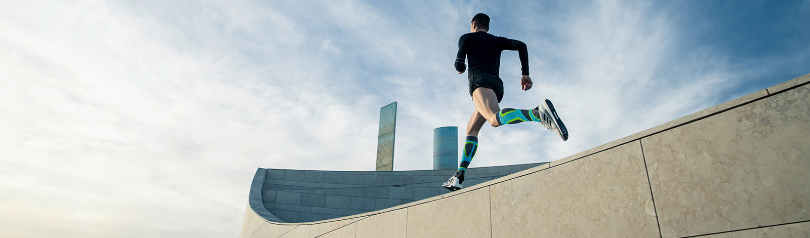 Young woman stretching while wearing the Run Performance Compression Socks before an inner-city run. Young woman stretching while wearing Bauerfeind's Run Performance Compression Socks before an inner-city run.
