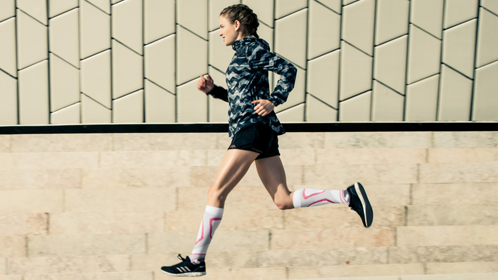 Woman wearing the Run Performance Compression Socks while running through a city street. Woman wearing Bauerfeind's Run Performance Compression Socks while running through a city street.