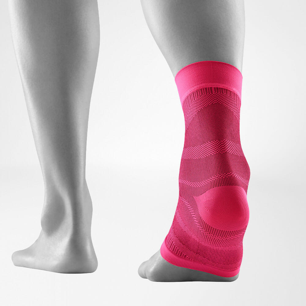 Side and back view of a leg wearing a pink compression ankle support sleeve.