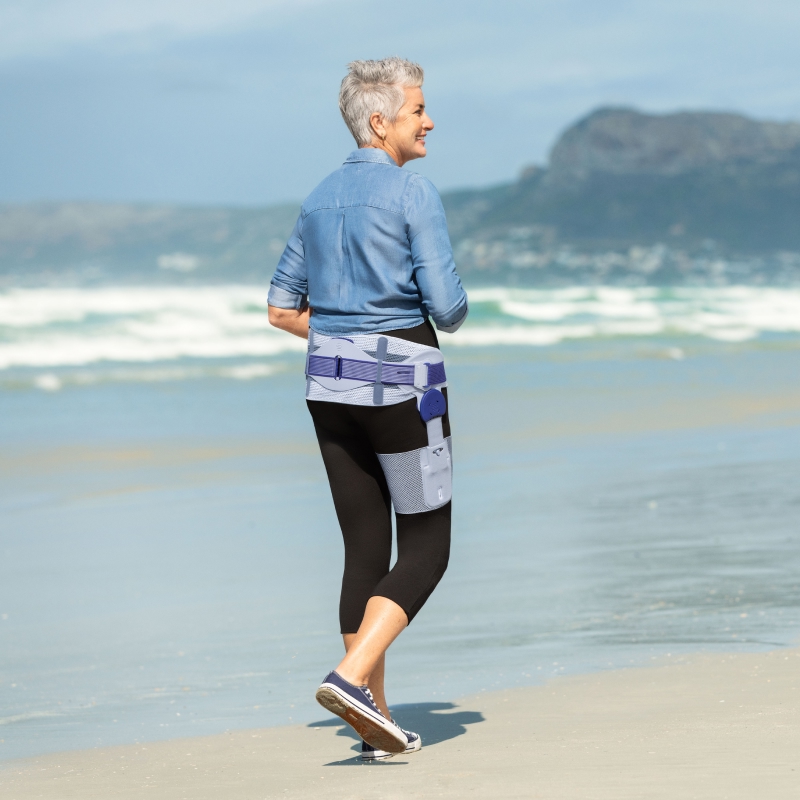 Woman wears Bauerfeind's CoxaTrain osteoarthritis hip brace on the beach.