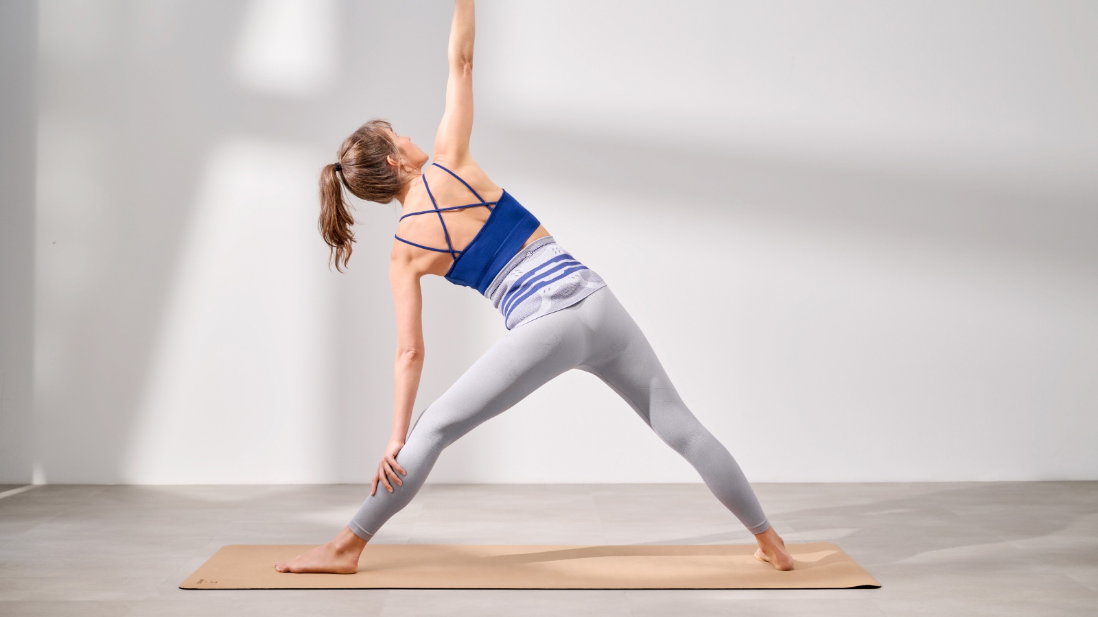 Woman practicing yoga pose on wooden dock by mountain lake.