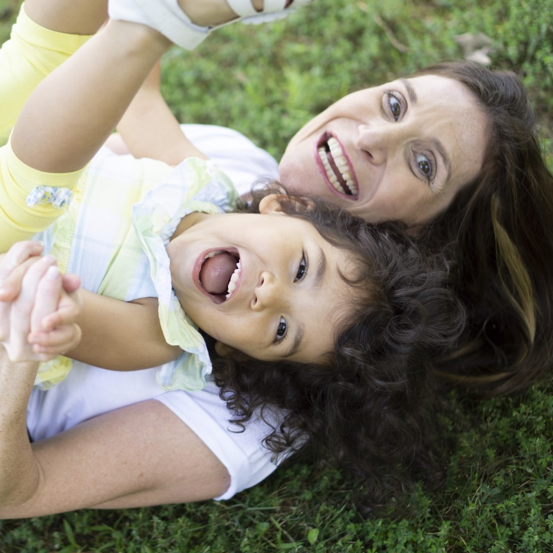 Mother and daughter playing and laughing together on grass. Mother and daughter playing and laughing together on grass, capturing a joyful moment outdoors.