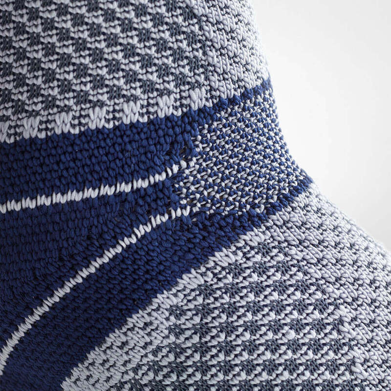 Durable Blue Ankle Brace for Enhanced Support and Mobility Close-up of a person wearing a modern blue ankle compression brace on one leg against a gray background, highlighting the support features and sleek design of the brace.