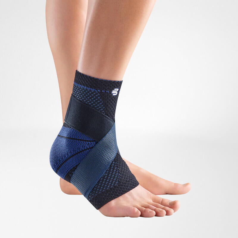 Close-up of a black and blue ankle brace on a person's left foot against a light gray background