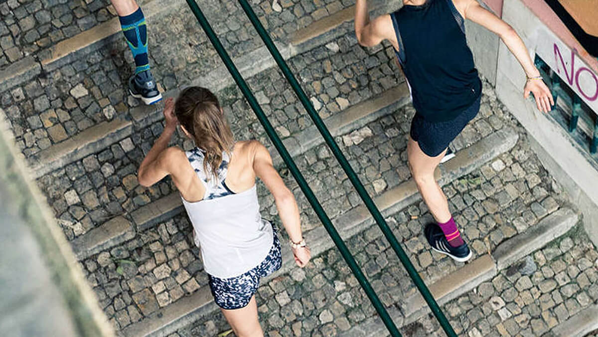 Urban Staircase Running - Fitness Challenge in the City Two people running up a cobblestone staircase outdoors, focusing on their fitness training.