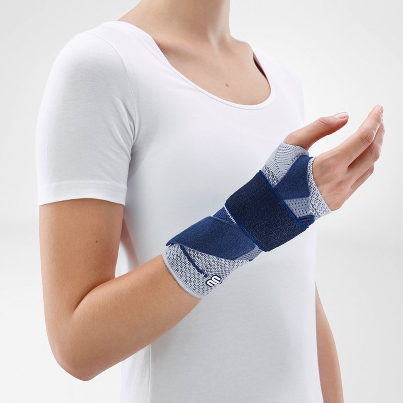 Woman wearing Bauerfeind's ManuTrain wrist brace (titan) while standing in front of a gray background.